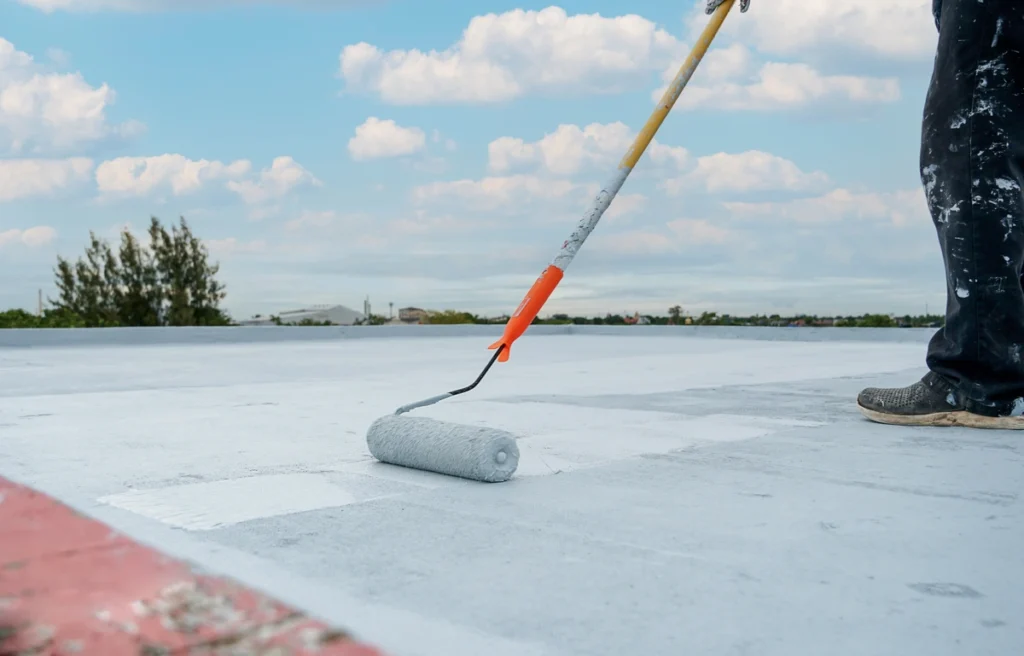 roofing contractor applies roof coatings with rolling brush